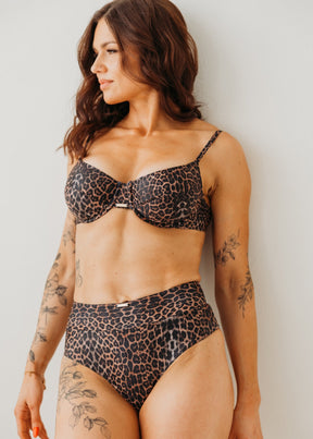 Woman wearing a leopard print bikini against a plain background