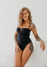 Woman wearing a black swimsuit with tattoos on a white background
